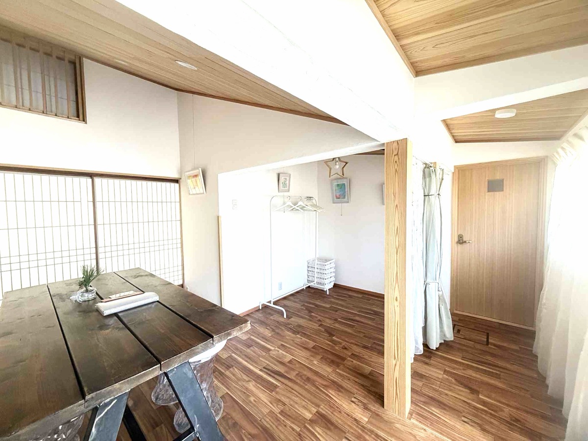 木のテーブルと白い壁の、明るい洋室